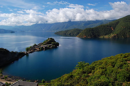 body of water beside mountain under cloudy sky during daytime thumbnail