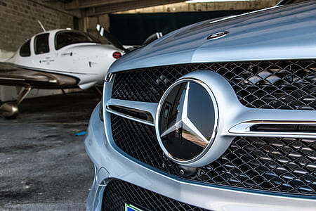 close-up photography of silver Mercedes-Benz vehicle beside white plane thumbnail