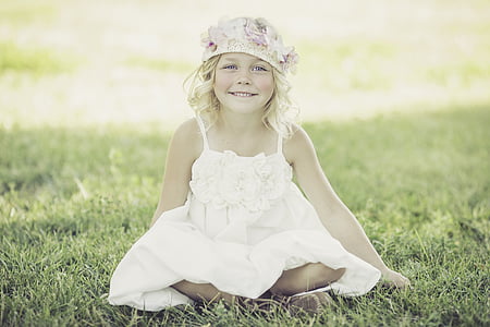 girl in white dress sitting on green grass field during daytime thumbnail
