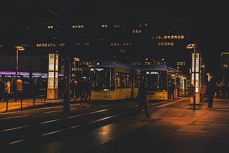 person walking on sidewalk near yellow trains thumbnail