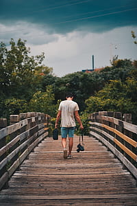 man holding DSLR camera while walking on bridge thumbnail