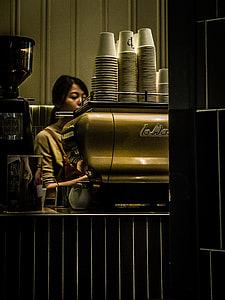 woman operating gray metal espresso maker inside well lighted room thumbnail