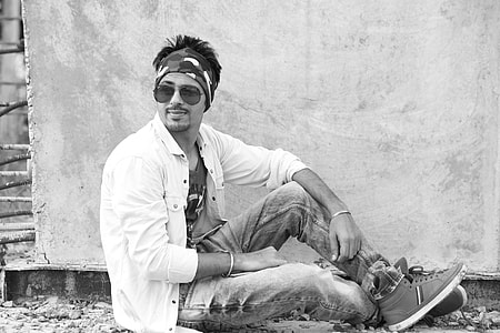 grayscale photography of man sitting on ground near wall thumbnail