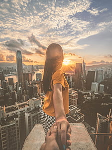 woman stands on platform while holding hands during golden hour thumbnail