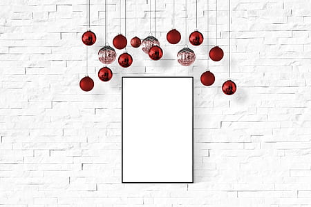 red Christmas baubles hanging behind white painted surface thumbnail