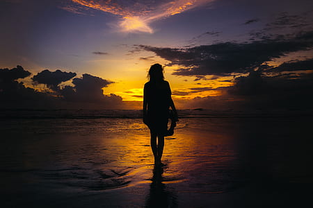 woman walking on sea during sunset thumbnail