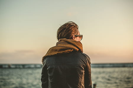 person wearing brown scarf and black leather jacket during daytime thumbnail