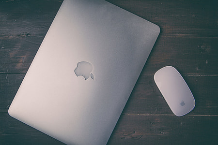Grainy overhead shot of a Apple Macbook Pro retina and magic mouse sitting on a wooden desk thumbnail