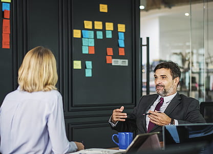 man sitting on chair talking to woman near table thumbnail