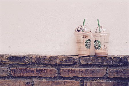 two empty Starbucks disposable cups on wall thumbnail