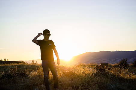 Man Standing on Grass Field Overlooking Sunrise thumbnail