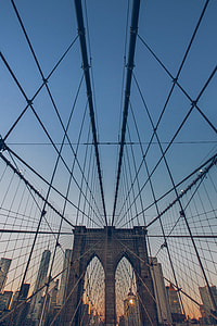 worm's eye view of suspension bridge under blue sky during sunrise thumbnail