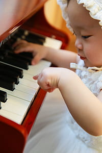 baby wearing white mesh sleeveless dress playing piano photography thumbnail