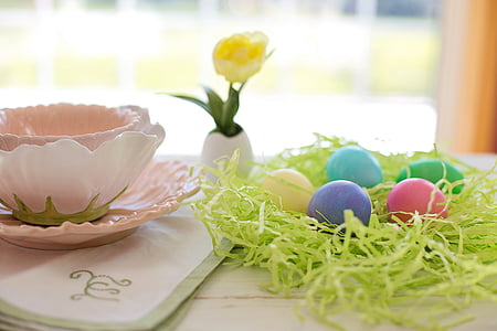 five assorted-color eggs on table beside a teacup on coaster thumbnail