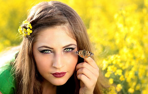woman wearing green top with brown and black butterfly on her hand at daytime thumbnail