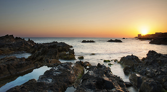 rock groynes and calm waves during sunrise thumbnail