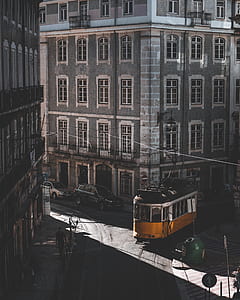 yellow tram passing beside building thumbnail