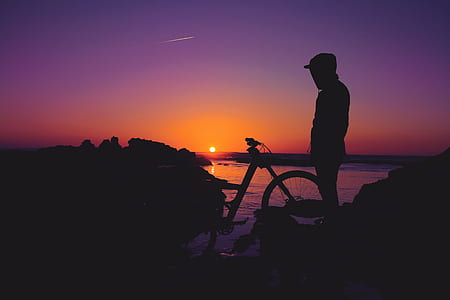 silhouette of person standing near bicycle during golden hour thumbnail