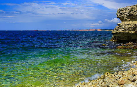 gray rock formation beside body of water during daytime thumbnail