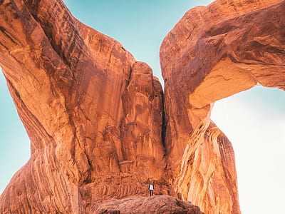 person standing on brown boulder during daytime thumbnail