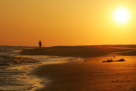Man walking in sand bear beach during sunset thumbnail
