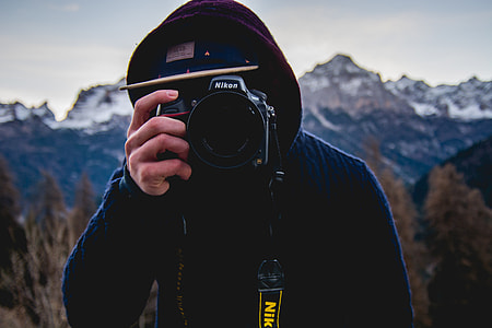 person holding Nikon camera near the mountain thumbnail