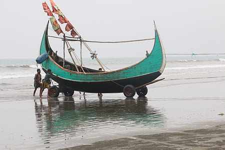 two people pushing teal and black boat thumbnail