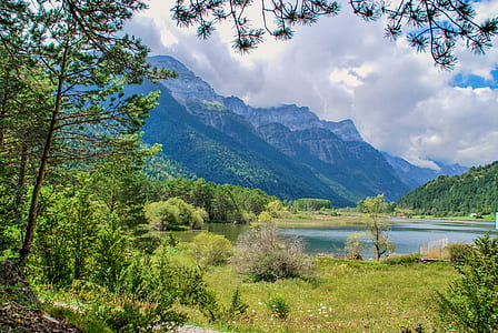 green mountain near trees and body of water during daytime thumbnail