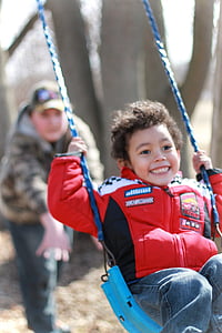 selective focus photo of boy swinging on teal chair thumbnail