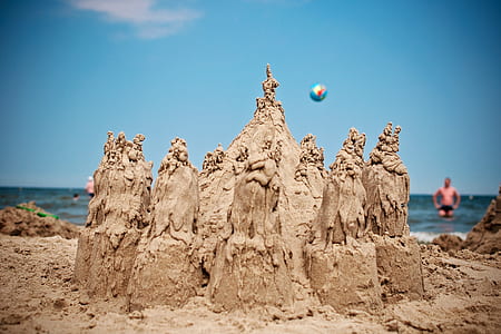 grey sand castle near shore during daytime thumbnail