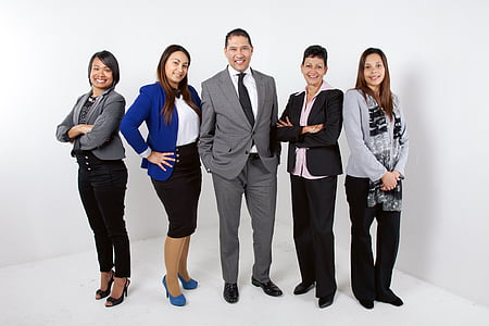 five people in formal clothing standing near white wall thumbnail