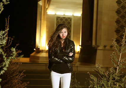 woman wearing bikers jacket standing near house in between of plant at night thumbnail