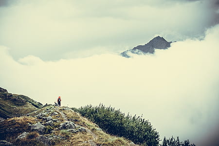 person standing on mountain top covered by clouds at daytime thumbnail