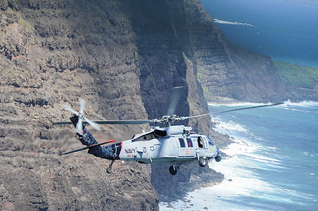 grey and black helicopter flying near mountain at daytime thumbnail