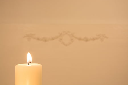 lighted white pillar candle near wall with hanged decor thumbnail