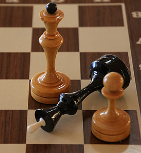black king chess piece in between two brown chess pieces thumbnail