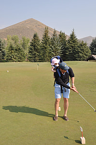 man carrying his son on back while playing golf thumbnail