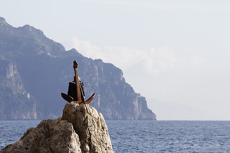 man sitting on top of rock surrounded with watert thumbnail