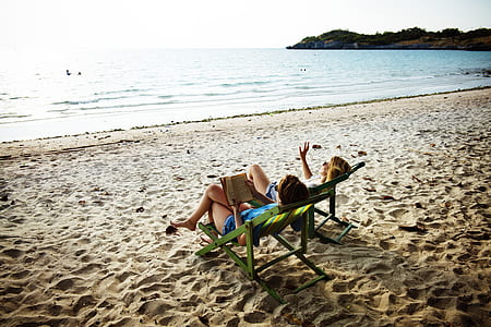 two women sitting on sling chairs in front of the sea thumbnail