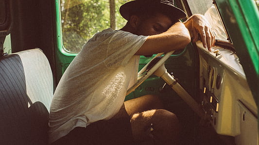 man in white t -shirt sleeping on top of white vehicle steering wheel thumbnail