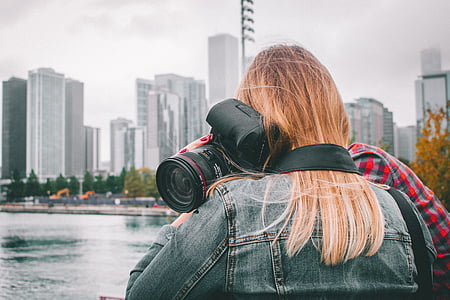 woman holding DSLR camera beside body of water thumbnail