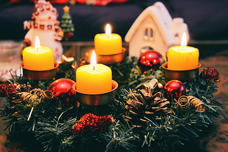 four yellow votive candles under green garland wreath thumbnail