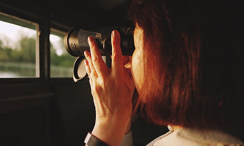 woman looking through binoculars near window thumbnail