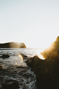 silhouette of rock formation near body of water thumbnail