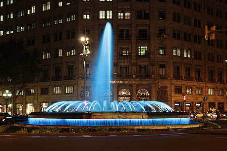 lighted fountain near building at nighttime thumbnail