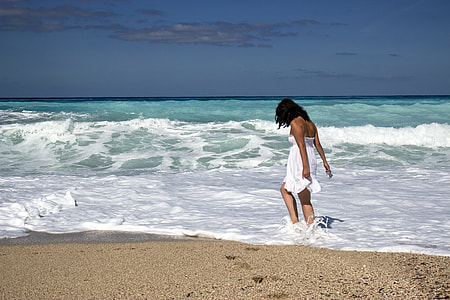 woman in white tube flare mini dress walking on seashore under blue sky during daytime thumbnail