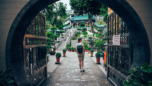 woman wearing white shirt and black leather backpack walking in pathway at daytime thumbnail