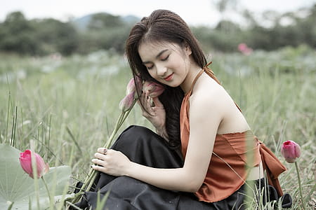 Woman Holding Flowers While Sitting thumbnail