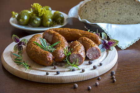 sausages placed on cutting board near bread and olives thumbnail