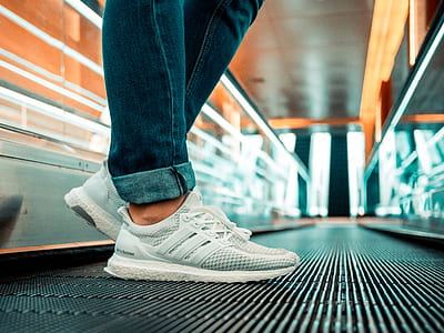 person standing on escalator wearing white adidas ultraBOOST running shoes thumbnail